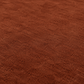 A close-up of a textured brown fabric surface with a soft, plush pile and subtle tonal variation.