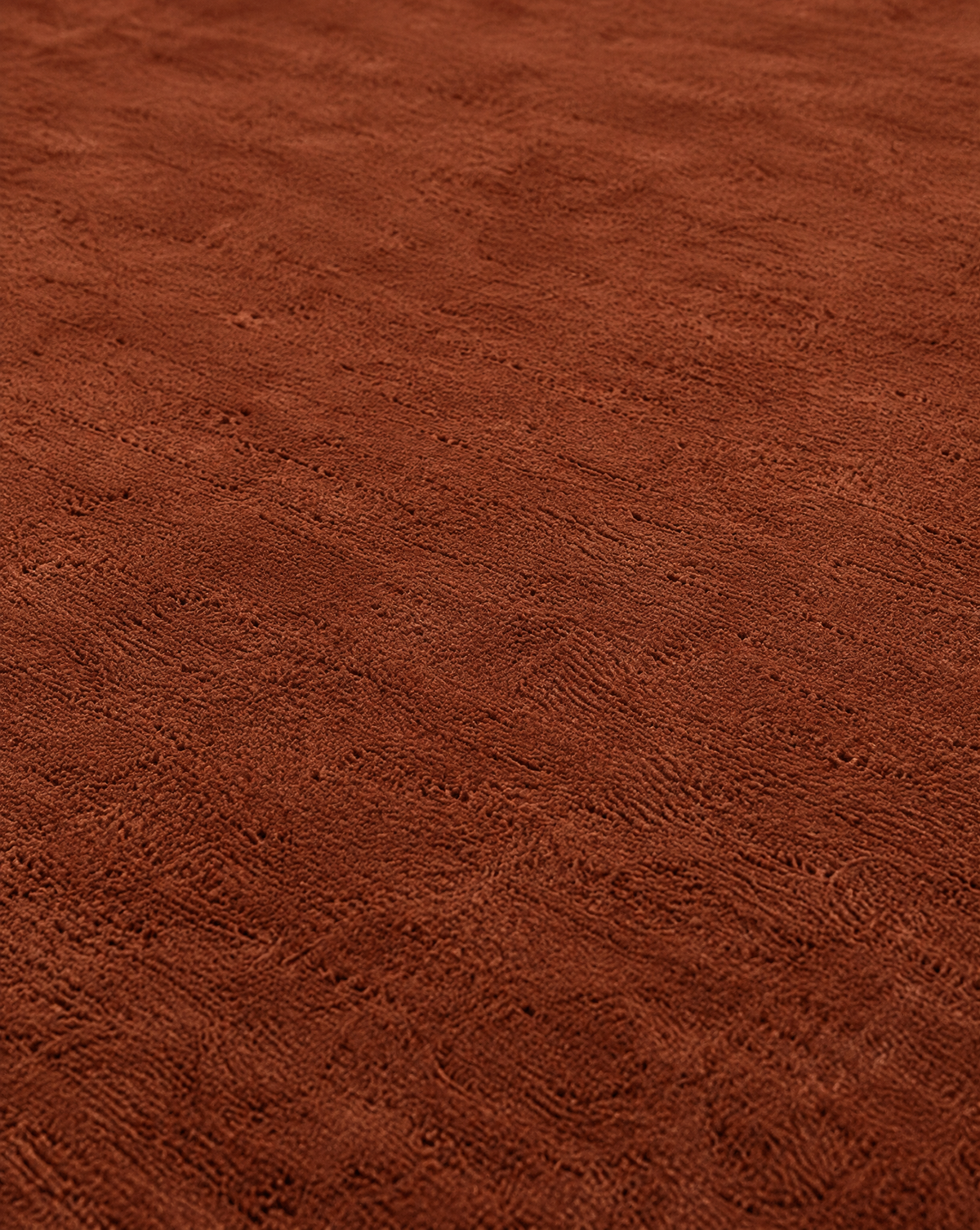 A close-up of a textured brown fabric surface with a soft, plush pile and subtle tonal variation.