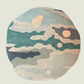 An abstract round area rug with a layered, coastal ocean pattern in muted teal, sage green, beige, and charcoal gray, accented with peach-colored sun-like circles, shown on a plain white background.