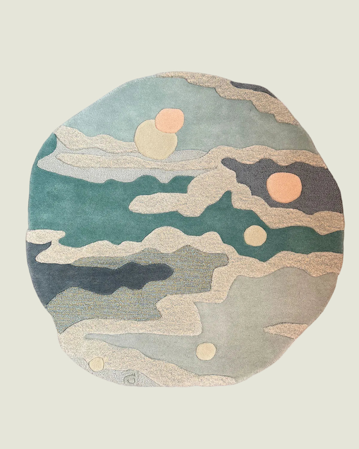 An abstract round area rug with a layered, coastal ocean pattern in muted teal, sage green, beige, and charcoal gray, accented with peach-colored sun-like circles, shown on a plain white background.