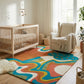 Daytrip Happy rug in a modern nursery with a crib, armchair, and natural wood floors. A colorful, abstract design.