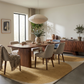 Modern dining room with a walnut table, upholstered chairs, and a mustard yellow area rug in a minimalist, warm interior.