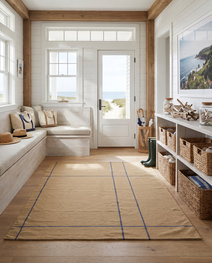 Popham Sand rug featuring a blue grid pattern in a bright, coastal-inspired entryway with bench seating and storage.