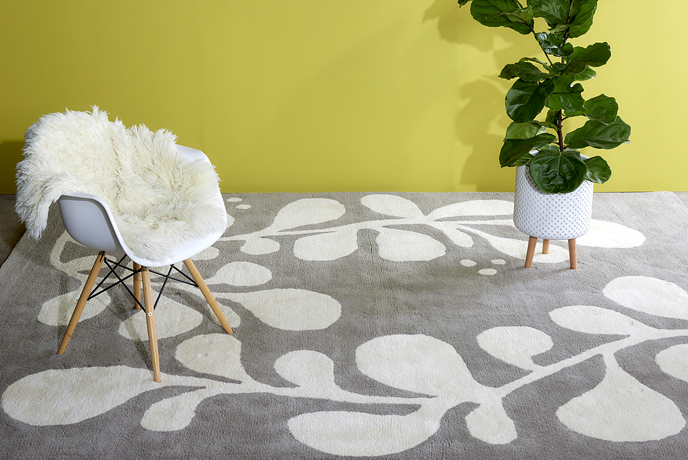 A modern area rug features white vines curving through gray new zealand wool