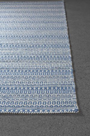 a detail corner of a blue, handmade area rug called Amma Fjara by angela adams
