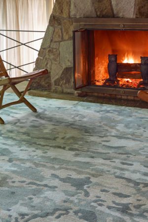 a textured area rug in front of a glowing fireplace