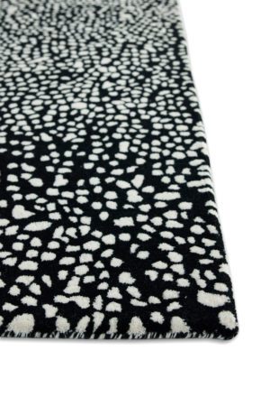 A corner detail of a black and white speckled area rug called Starry Onyx by Angela Adams