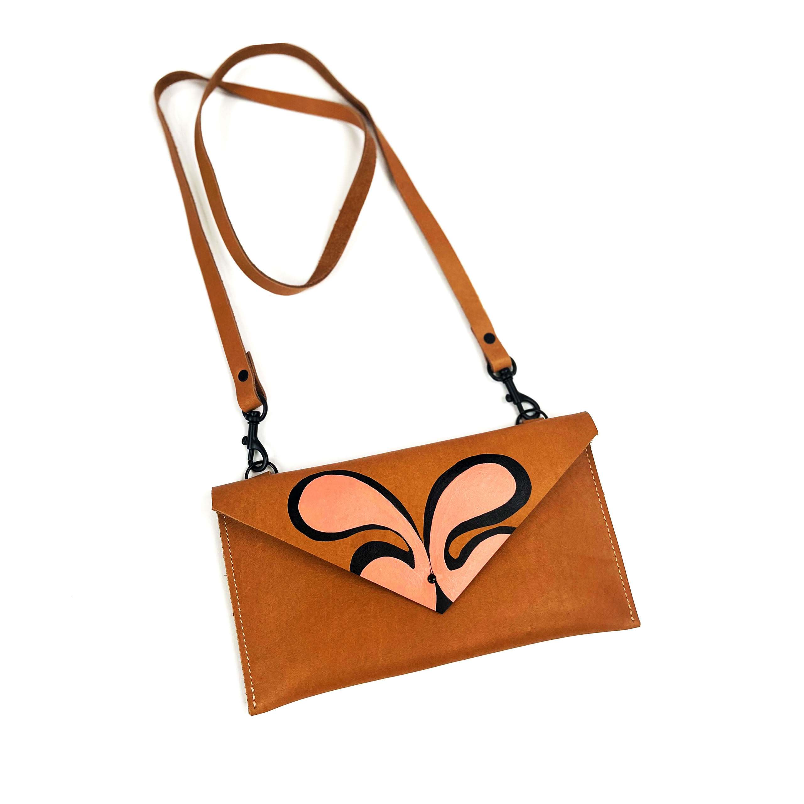 A brown and tan leather shoulder bag with a sparkling peach heart design, isolated on a white background.