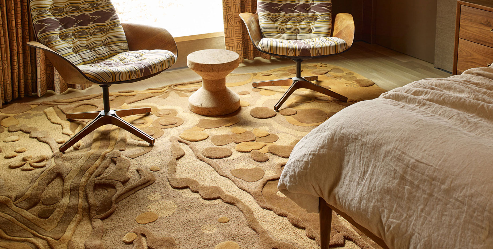 Two embroidered chairs in a sunlit bedroom with a beautiful, copper colored rug.