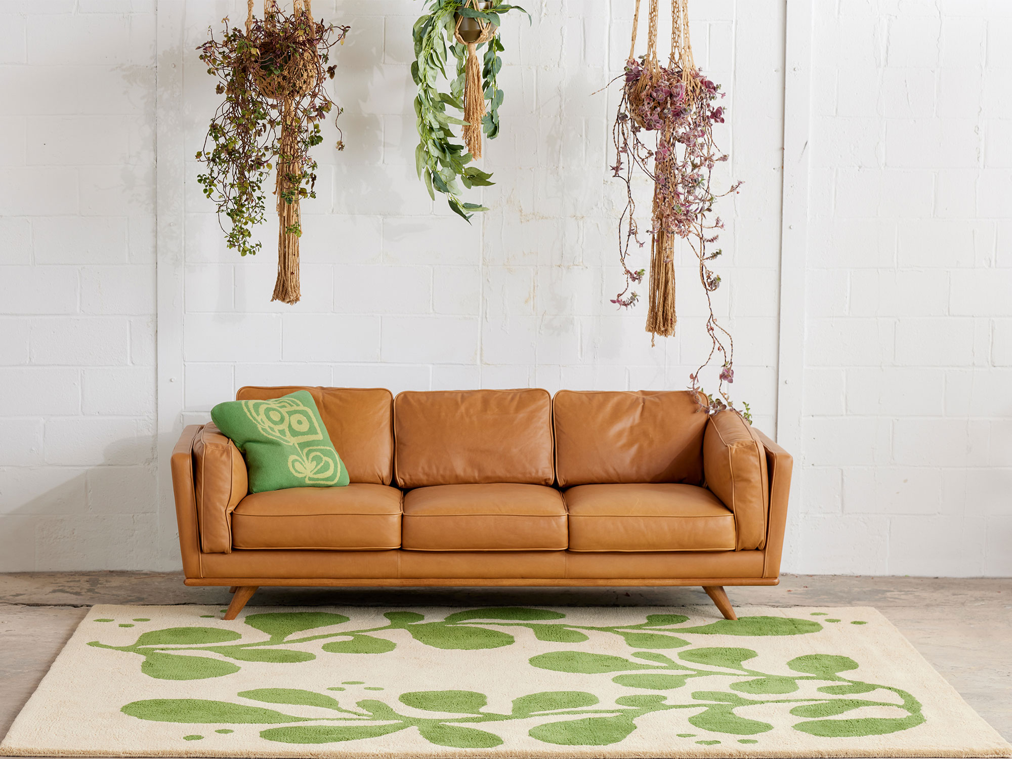 A leather sofa sits on a modern area rug called Vines Mambo by Angela Adams