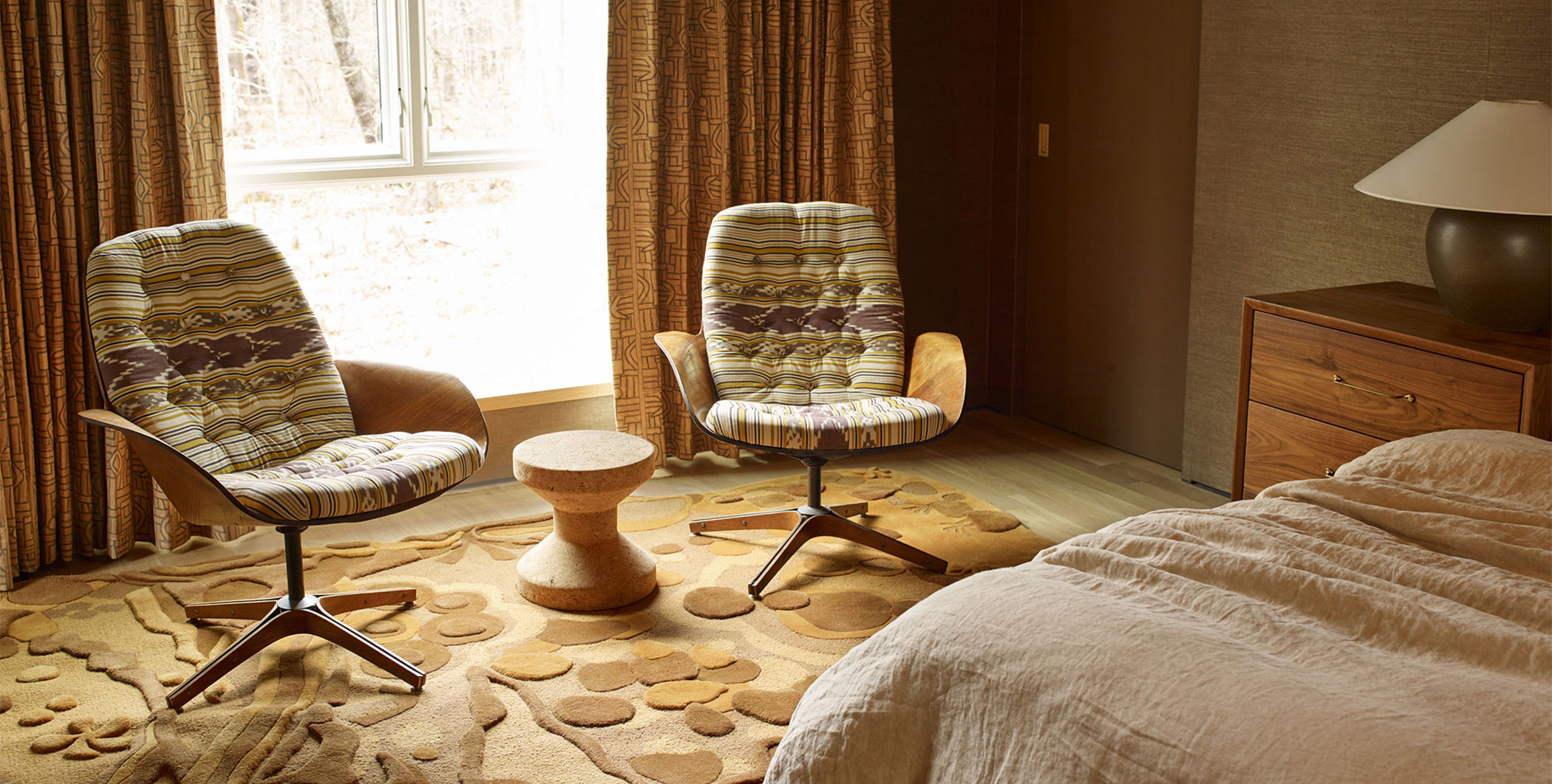 Two embroidered chairs in a sunlit bedroom with a beautiful, copper colored rug.