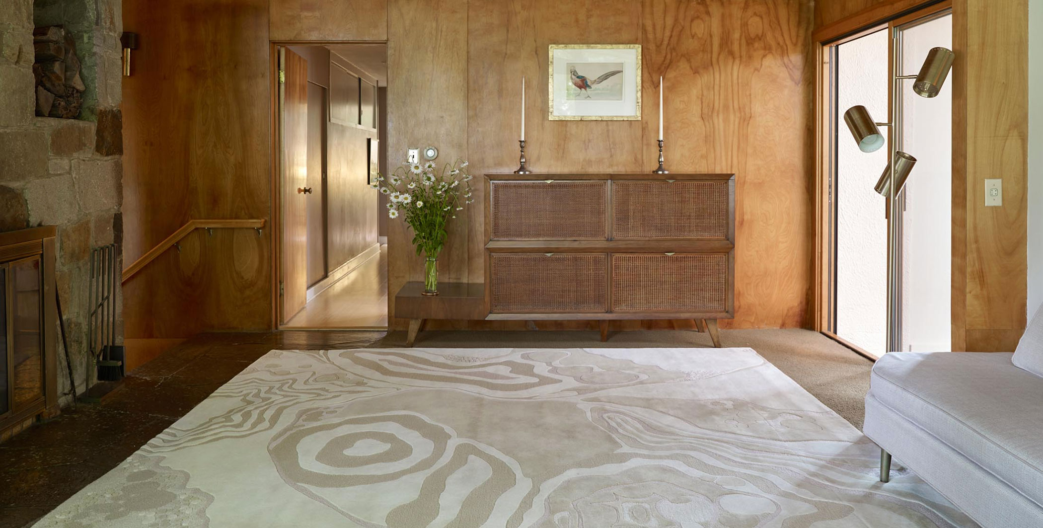 A beautiful, warm wood and soft fabrics living room with a modern white abstract patterned area rug in focus.