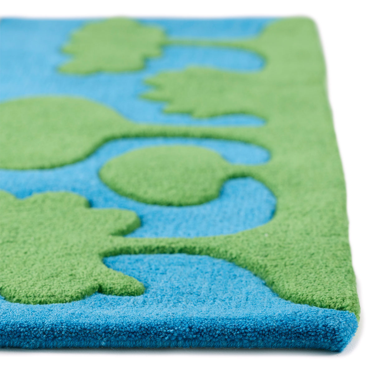 The corner of a small rug with green trees and blue sky.