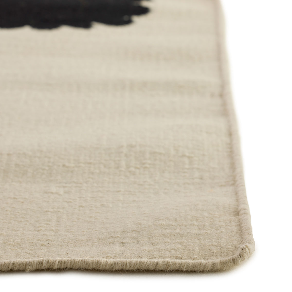 The corner detail of an abstract square beige and black green rug named Lovely Day Love.