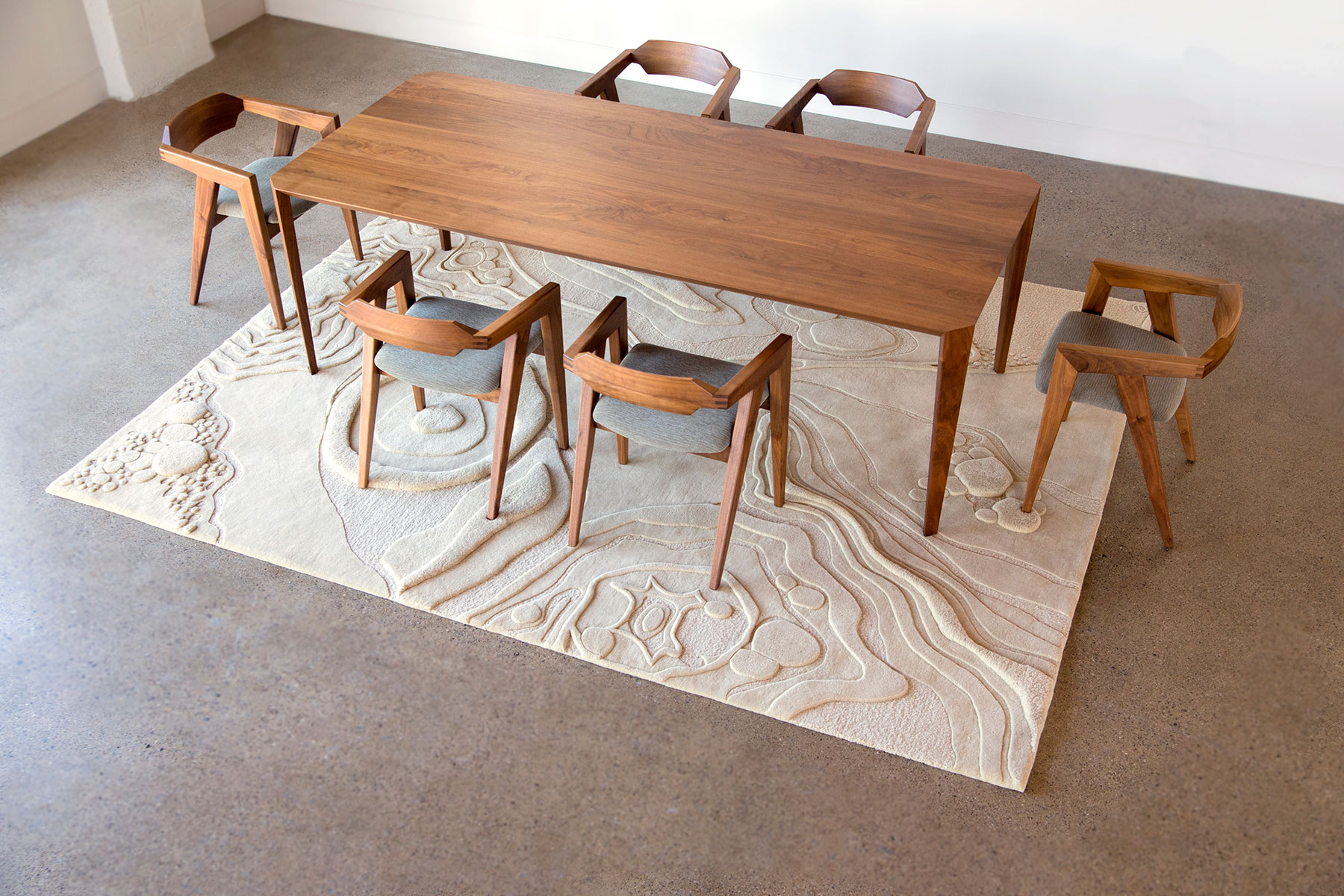 A dining room table sits on top of an organic patterned rug called Nebula