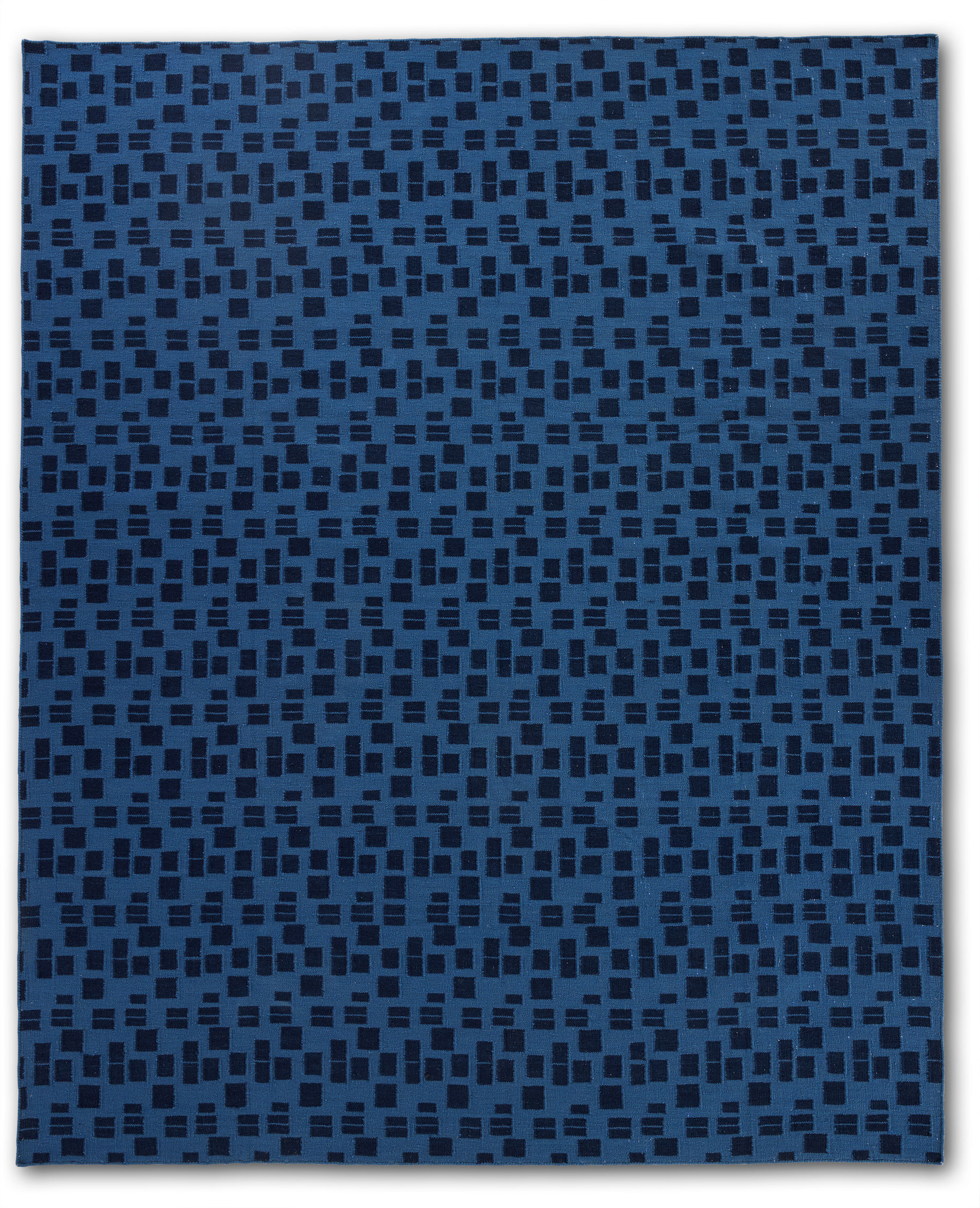 A close up of a jute area rug with blue rectangle patterns on a dark blue background.