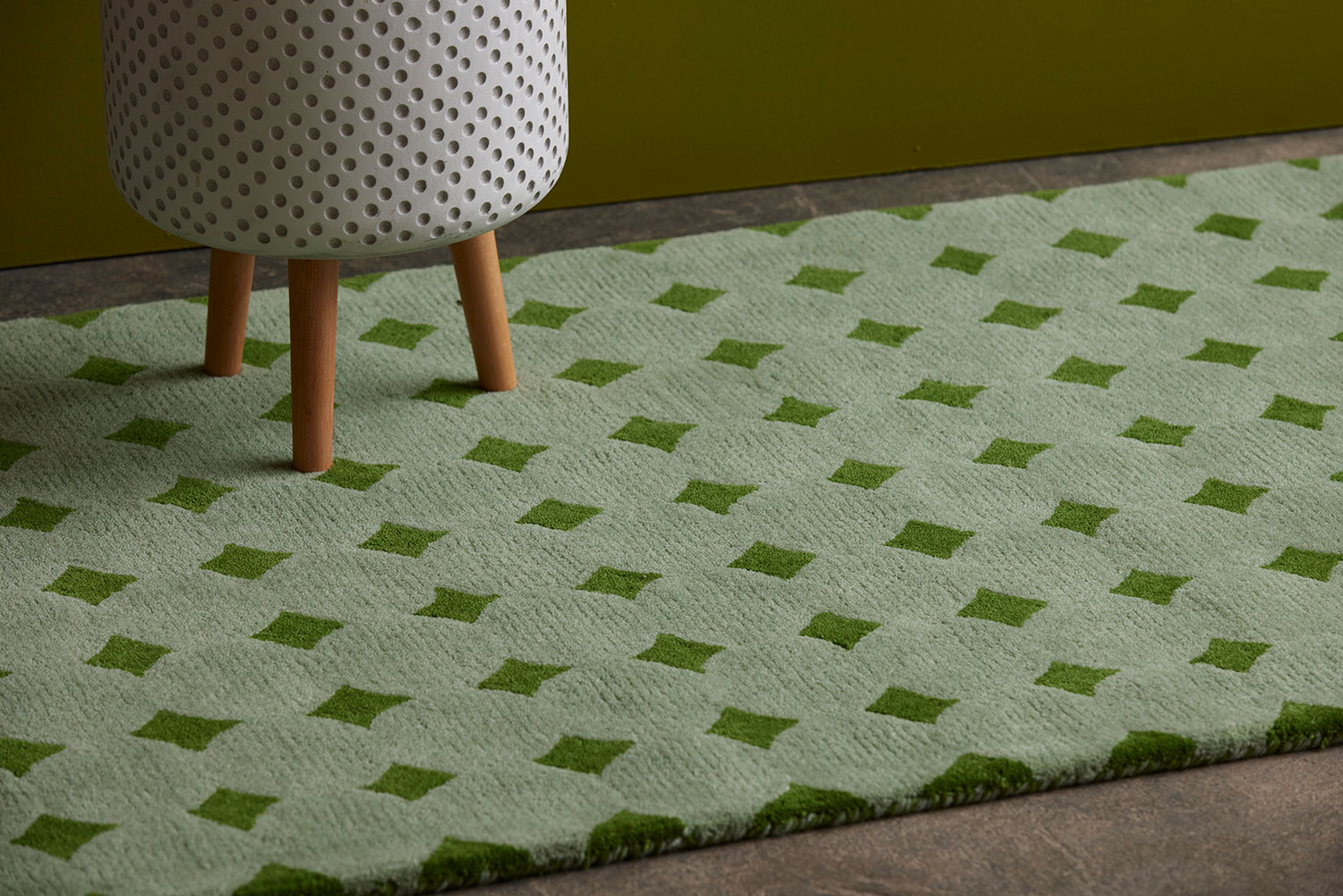 A green area rug called Bongo Fresca with a plant pot on it