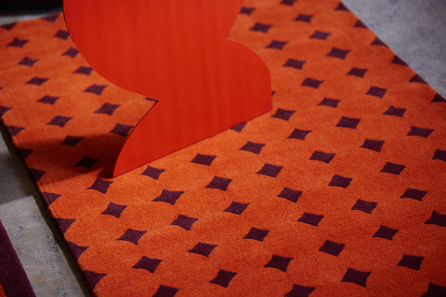 A close up of a cardboard red heart sits on top of a modern area rug in red called Bongo Passion