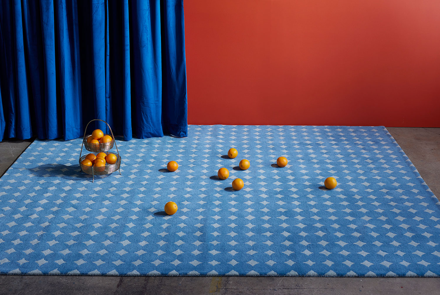 A blue area rug called Bongo Pool with oranges on it.