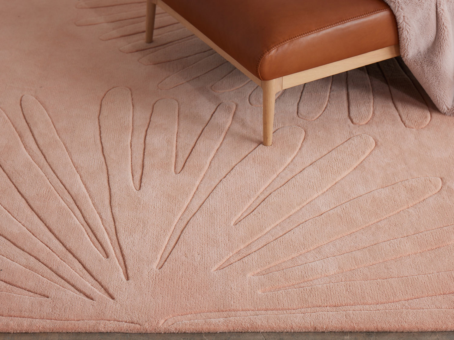 A leather and wood chair sit on a modern area rug in pink called Daisies Petal