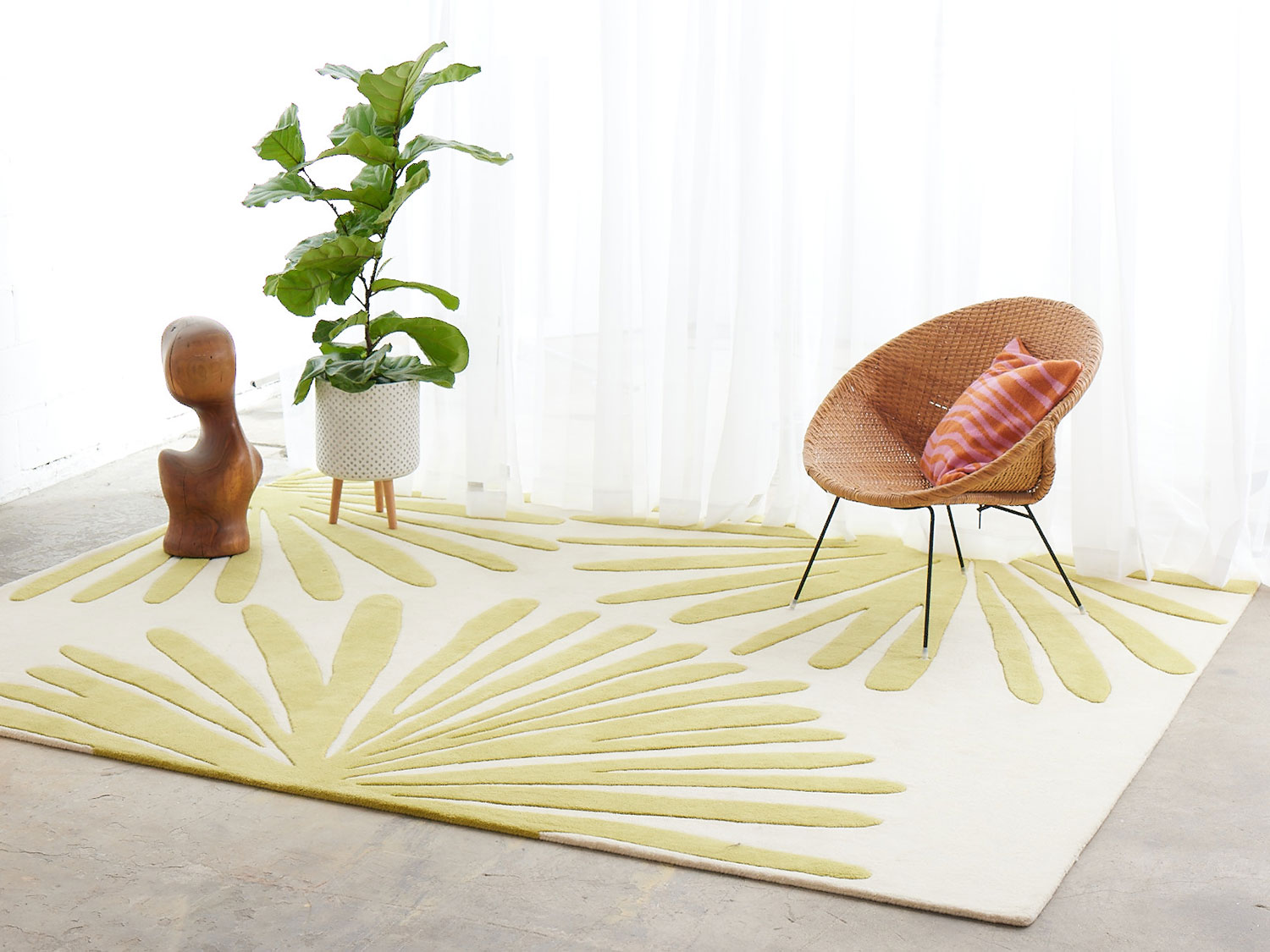 A white room with wicker chair, and plant on a modern area rug called Daisies Sunny