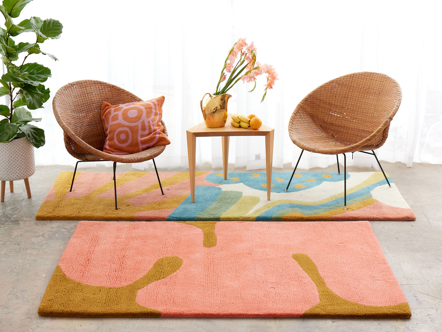A white room with wicker chairs on a multi-colored, modern area rug by Angela Adams called Daytrip Happy