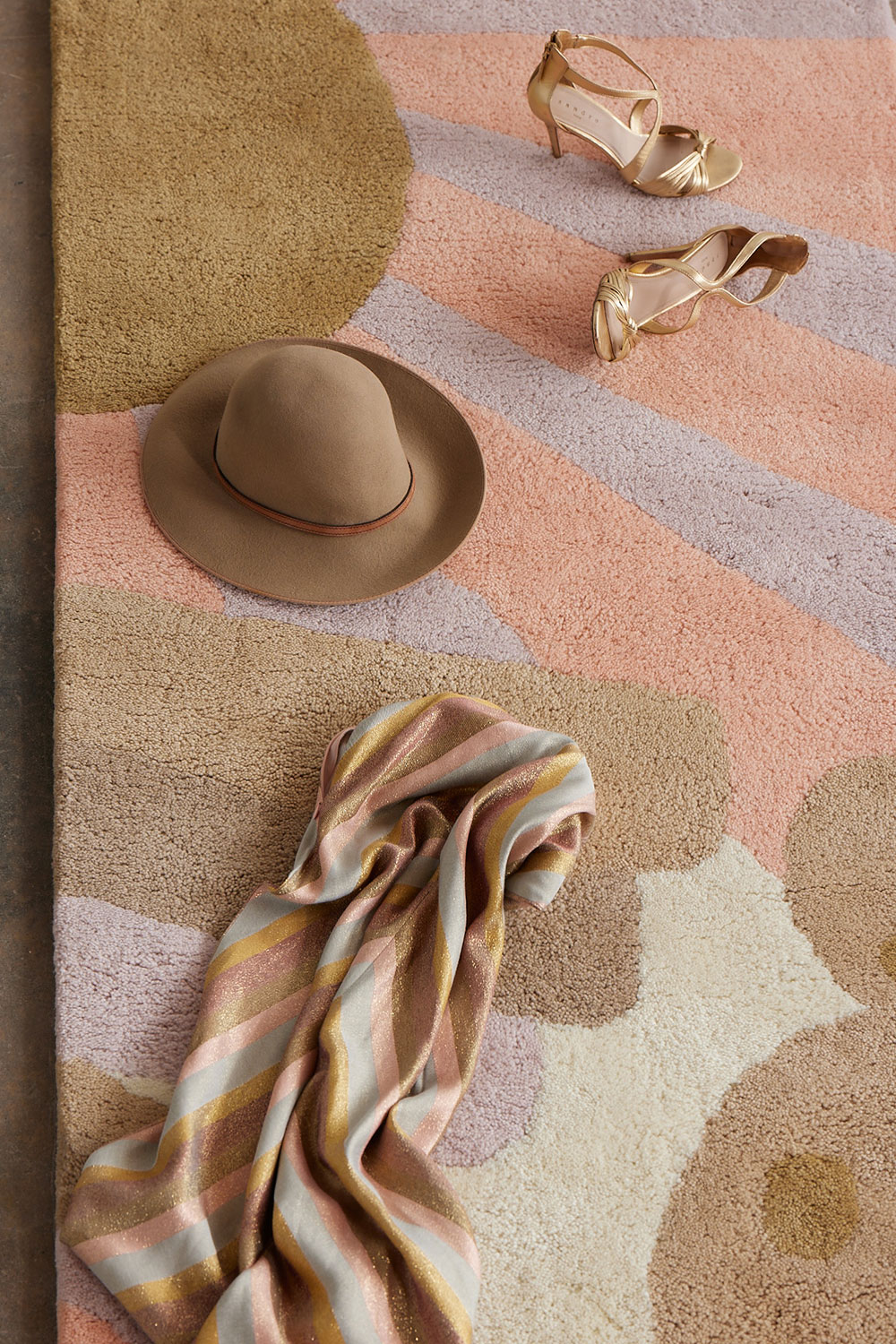 Hat, shoes, and scarf on a cream colored, modern area rug by Angela Adams called Daytrip Lovely