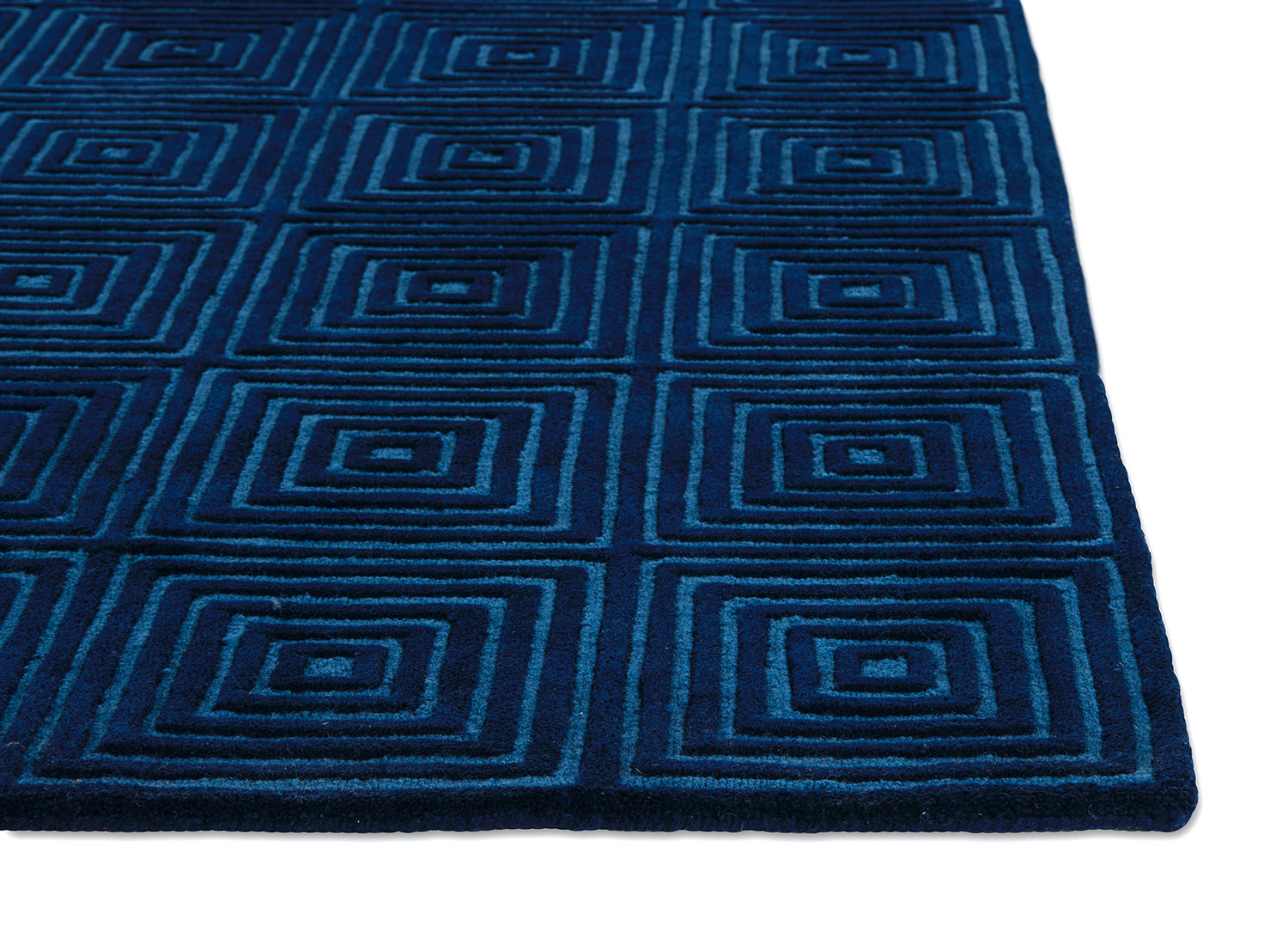 A corner of a deep blue, modern area rug called Duke Blue by Angela Adams