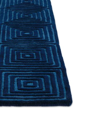 A corner of a deep blue, patterned, modern area rug called Duke Blue by Angela Adams
