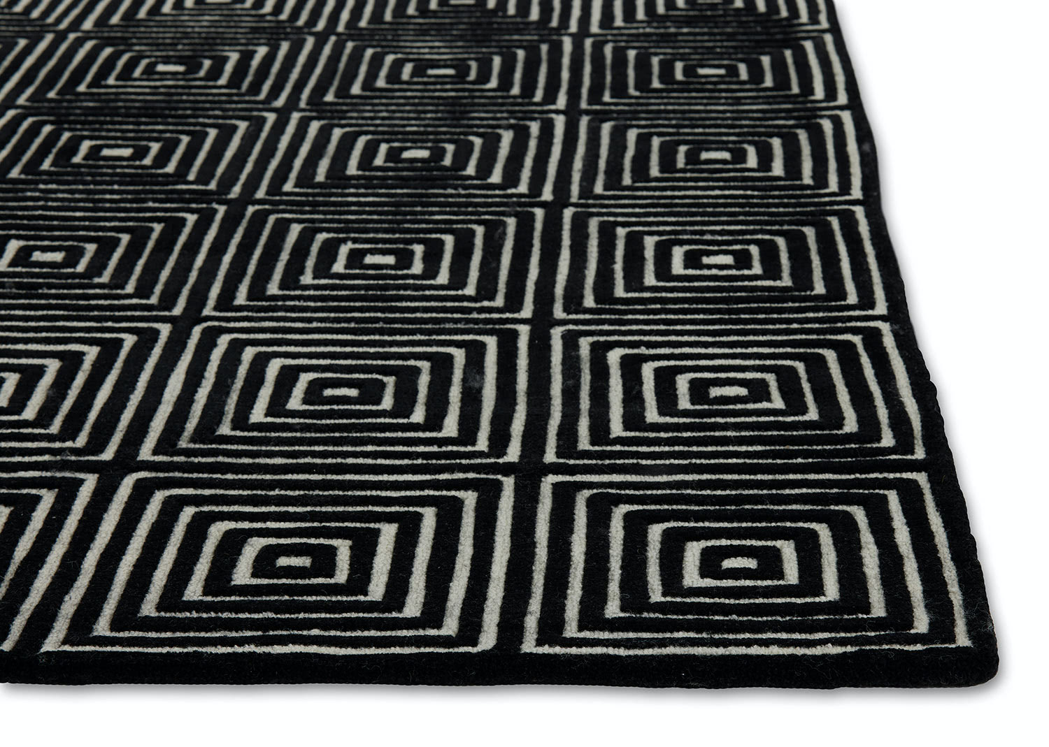 A corner of a black and white, patterned, modern area rug called Duke Vivid by Angela Adams