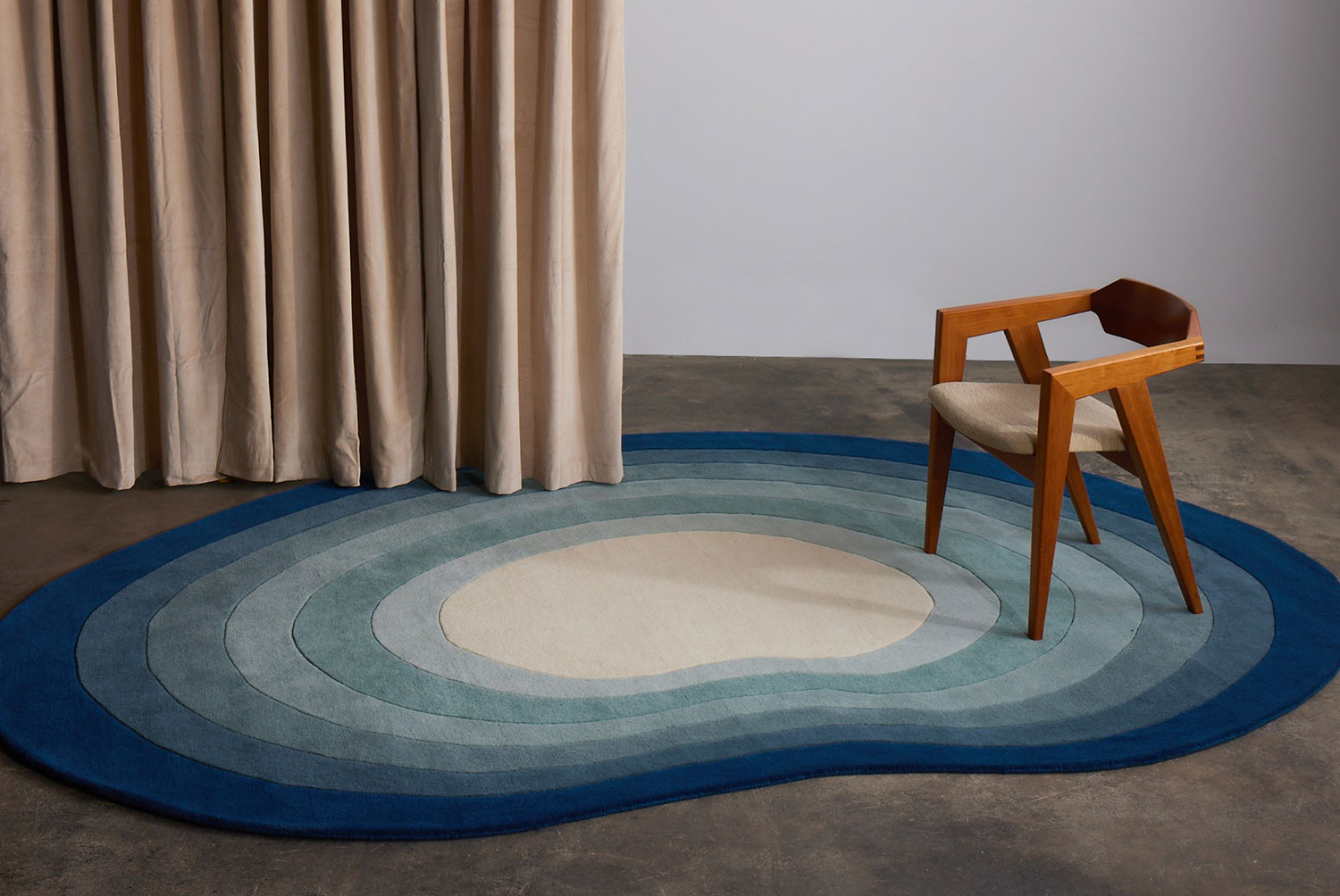 A blue gradient area rug called Pool Dream with a wooden chair on it.