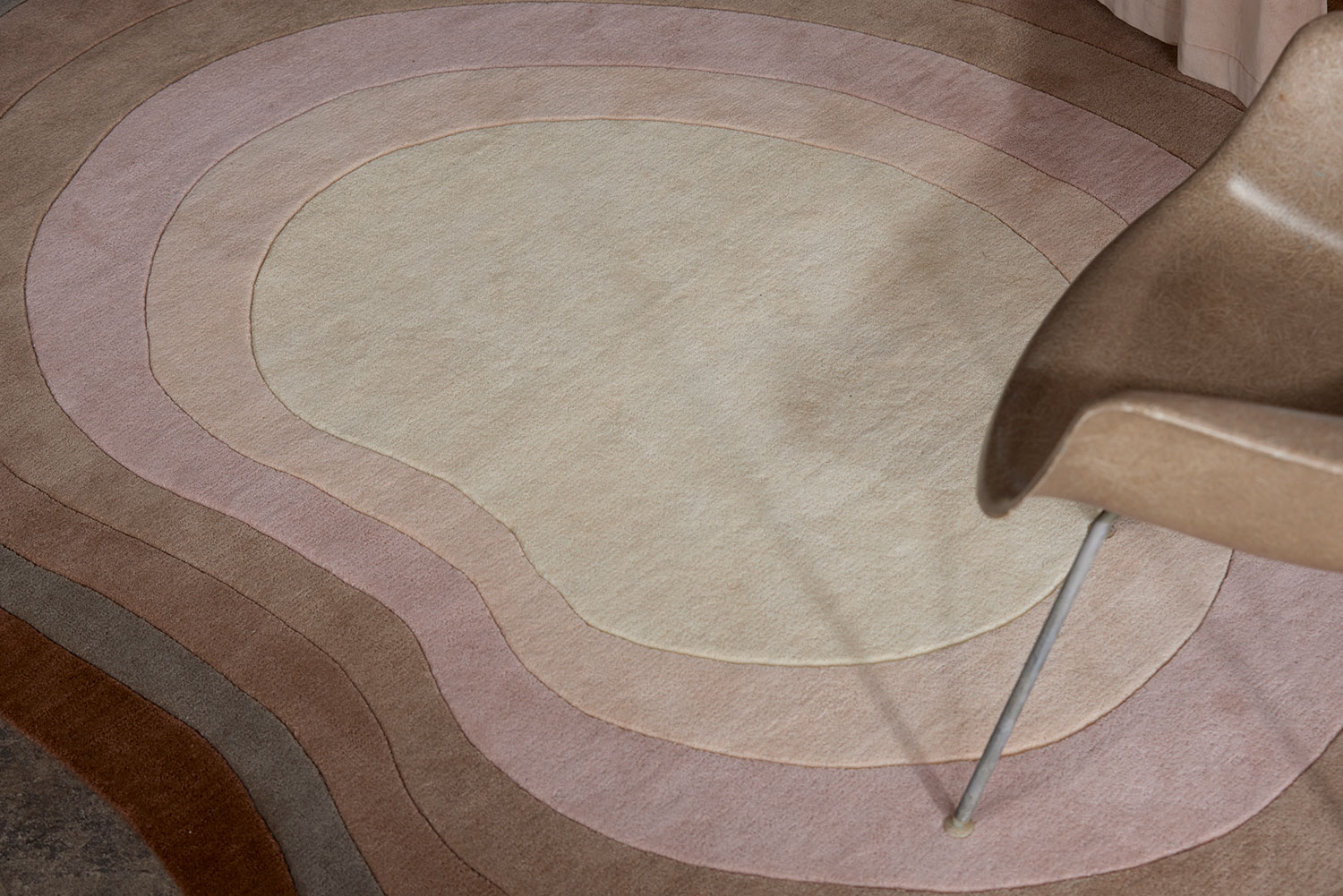 A chair sits on a neutral gradient area rug called Pool Heaven in the shape of a pool