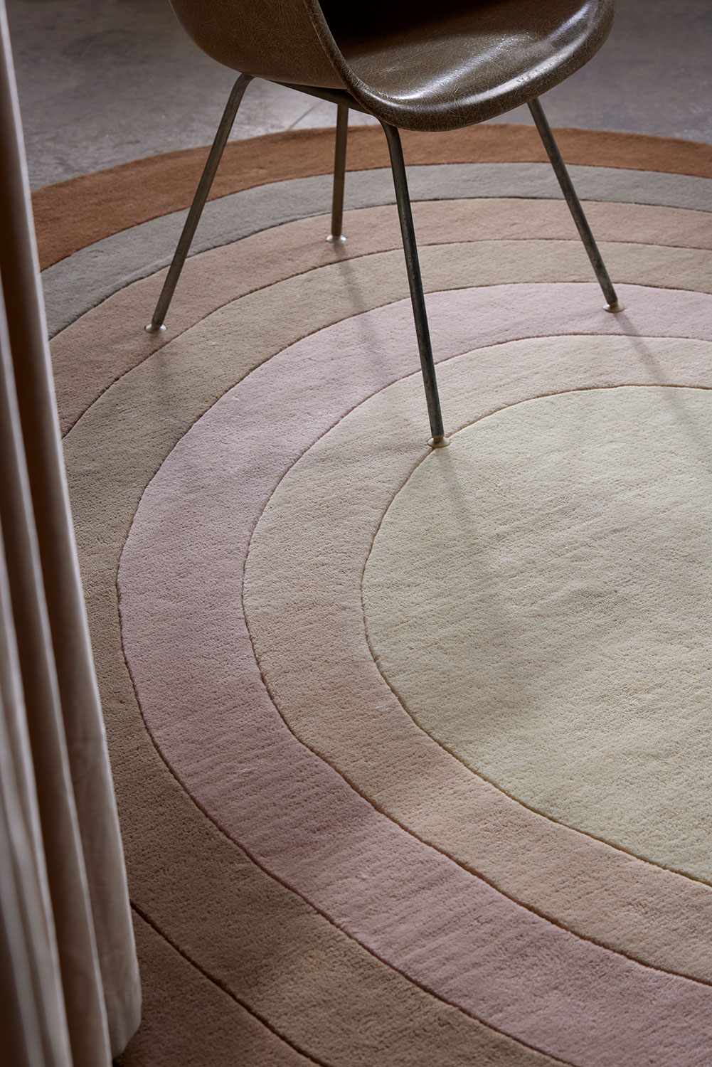 A chair sits on a neutral gradient area rug called Pool Heaven in the shape of a pool