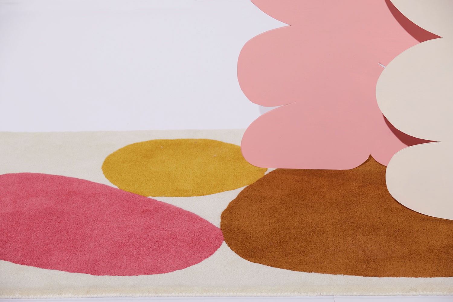 A pink, and a white card board cutout sit on a 3 foot by 5 foot modern rug called Three Stones Clay