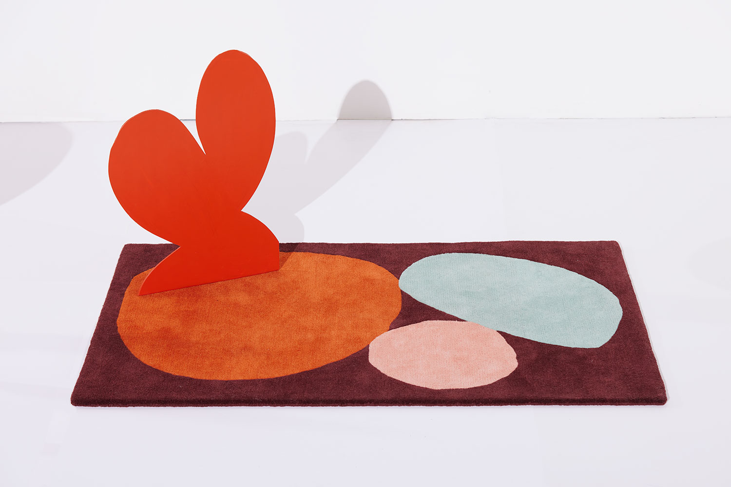 A cardboard heart cutout sits on a 3 foot by 5 foot modern rug called Three Stones Rust