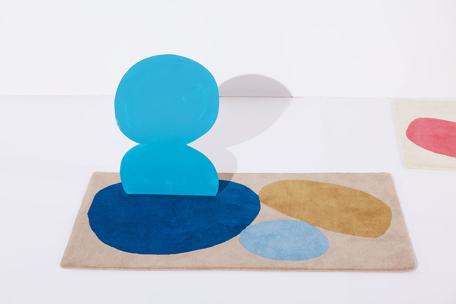 A 3 foot by 5 foot modern rug called Three Stones Sand with a blue shape and silhouette on top