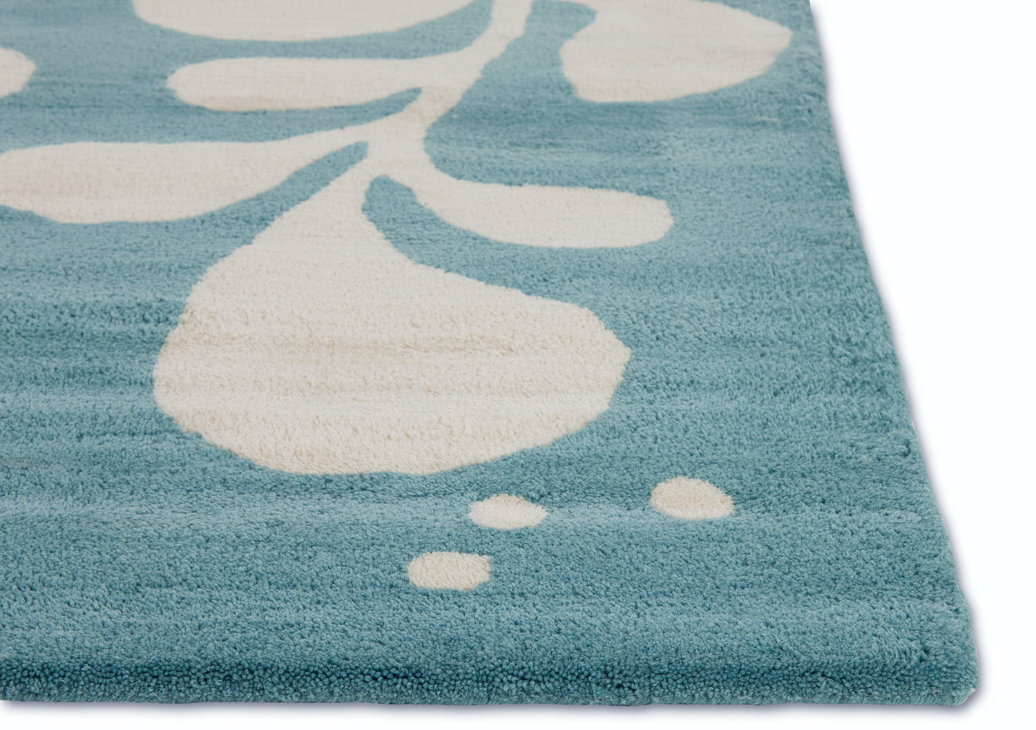 A corner detail of a neutral and blue area rug with abstract designs on it called Vine Hush