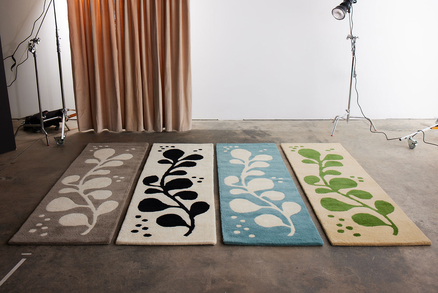 A group of runner rugs lined up in a studio space, these are called Vine Hush, Mambo, Swoosh, and Tango