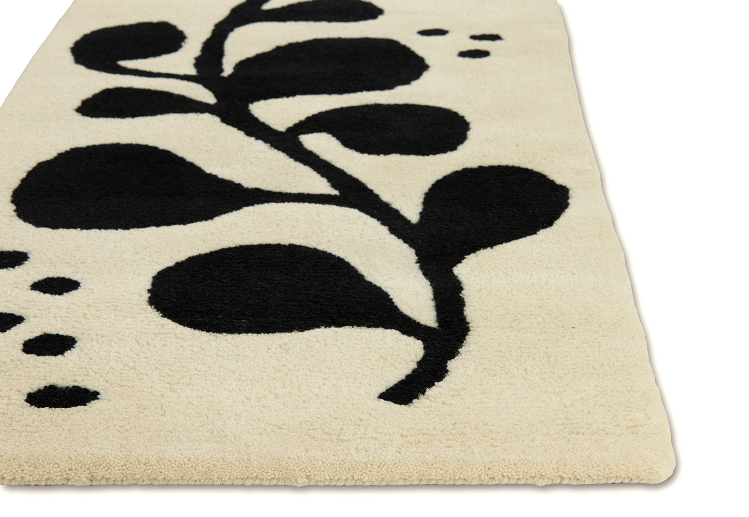 A corner detail of a neutral and black area rug with abstract designs on it called Vine Tango