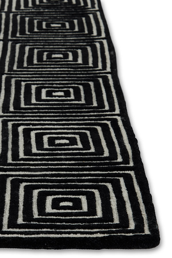 A corner of a black and white, patterned, modern area rug called Duke Vivid by Angela Adams