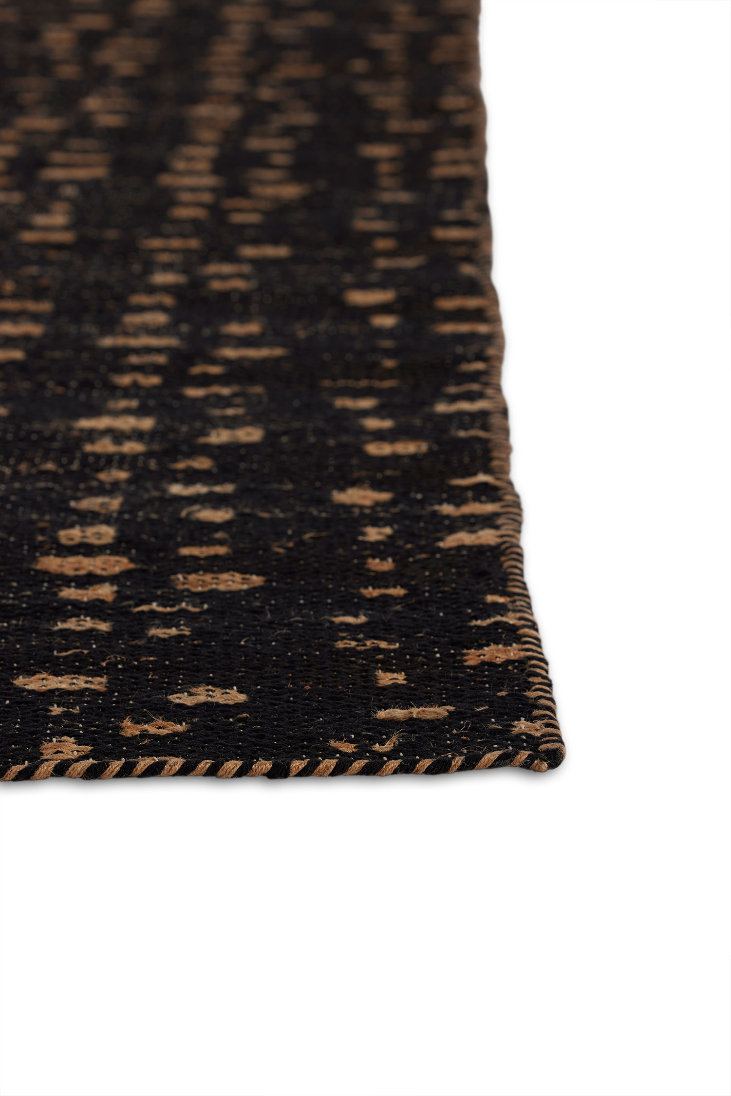 A close up of the corner of a jute area rug with tan stripe patterns on a dark brown background.