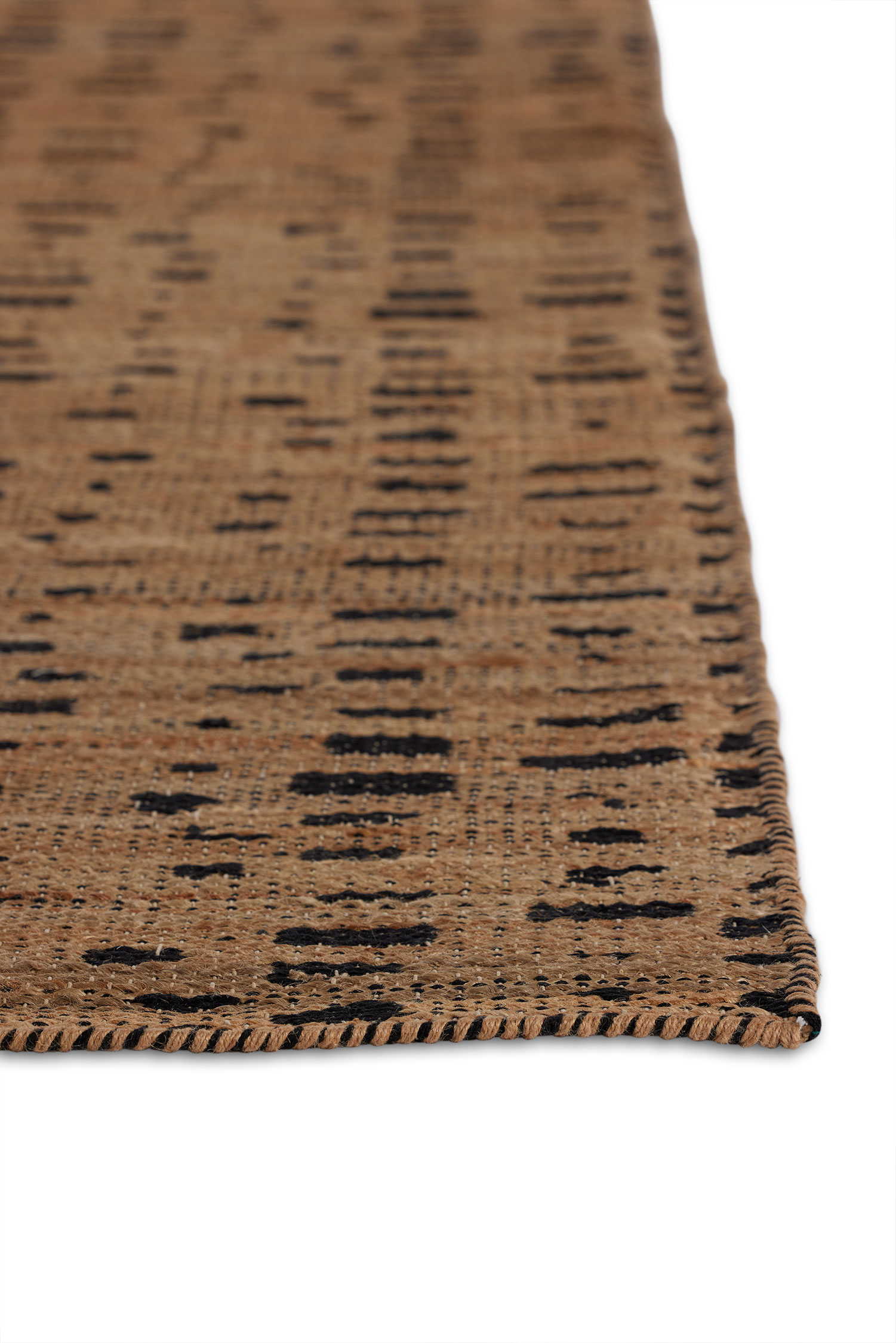 A close up of the corner of a jute area rug with brown stripe patterns on a light brown background.